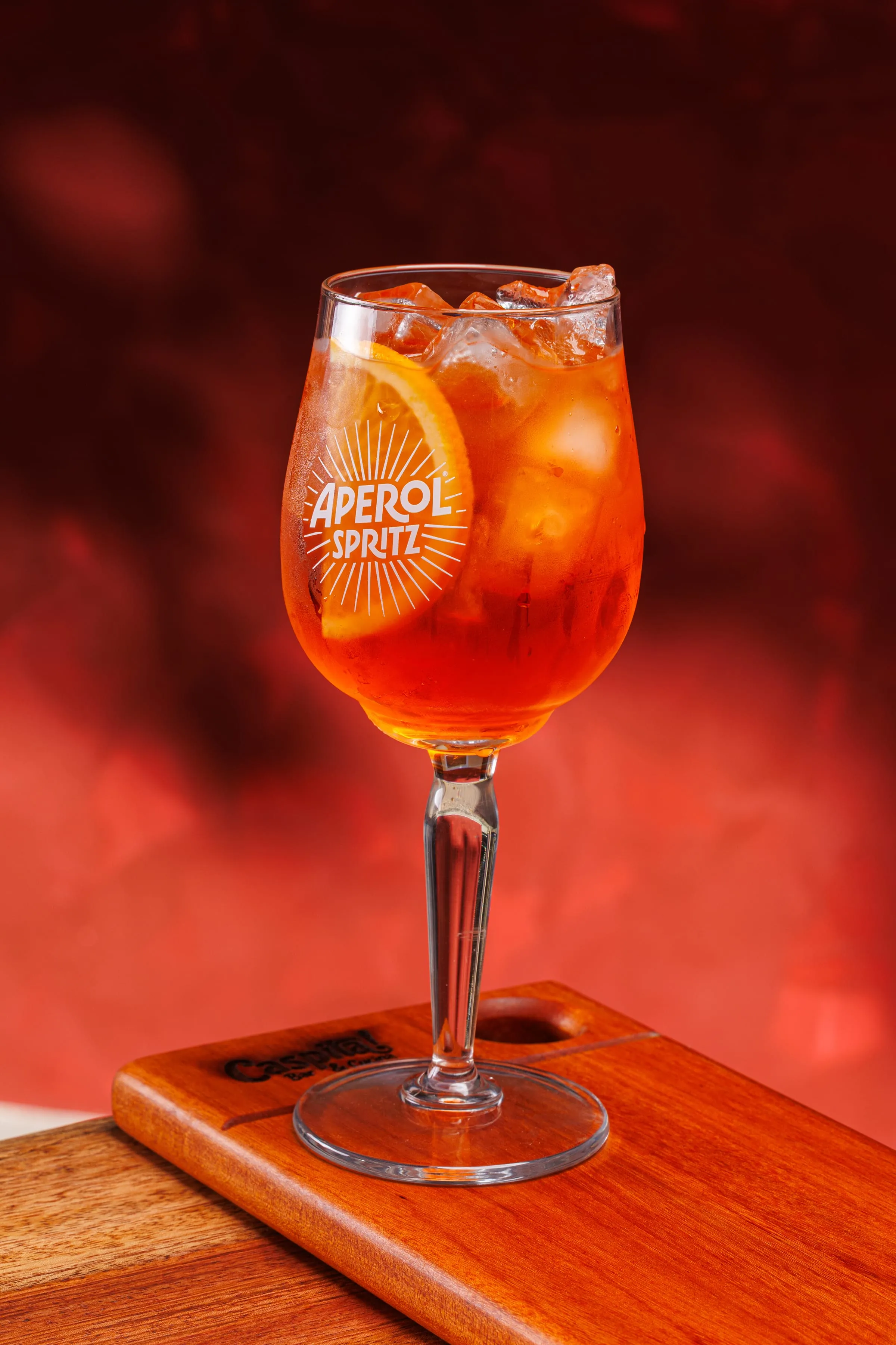 Aperol Spritz na taça, contra a parede vermelha do Caspita