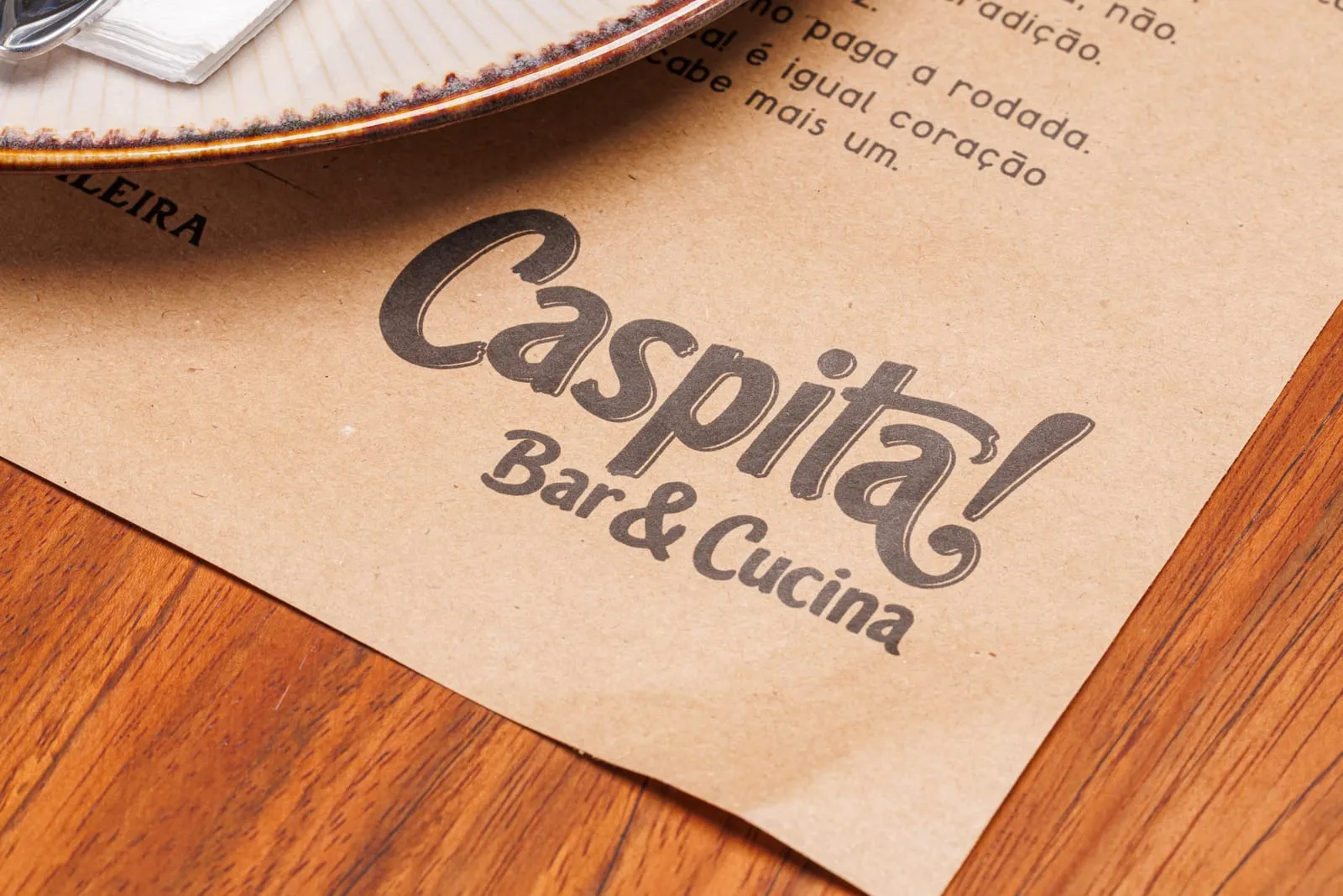 Placemat kraft do Caspita com a marca impressa, sobre a mesa de madeira