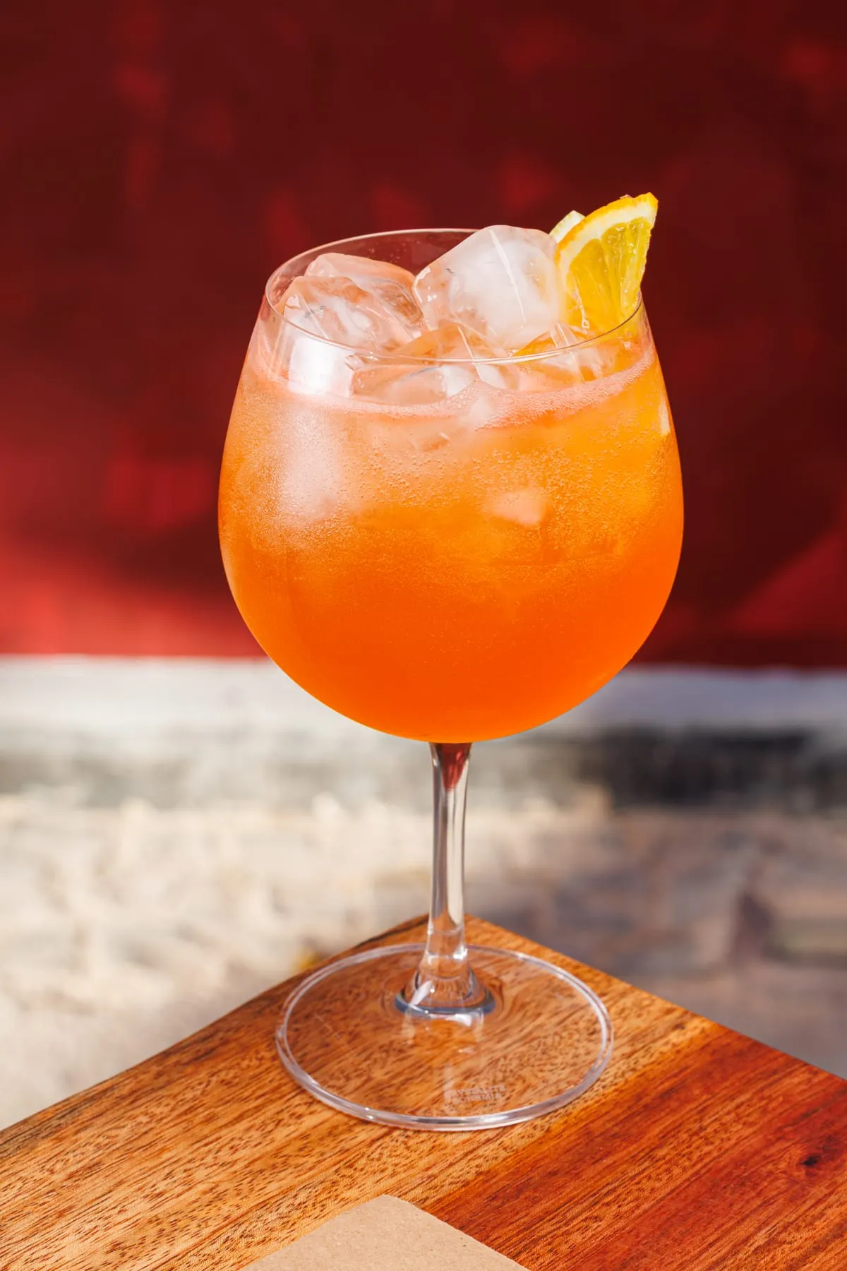Spritz da casa em taça grande, na luz quente do bar
